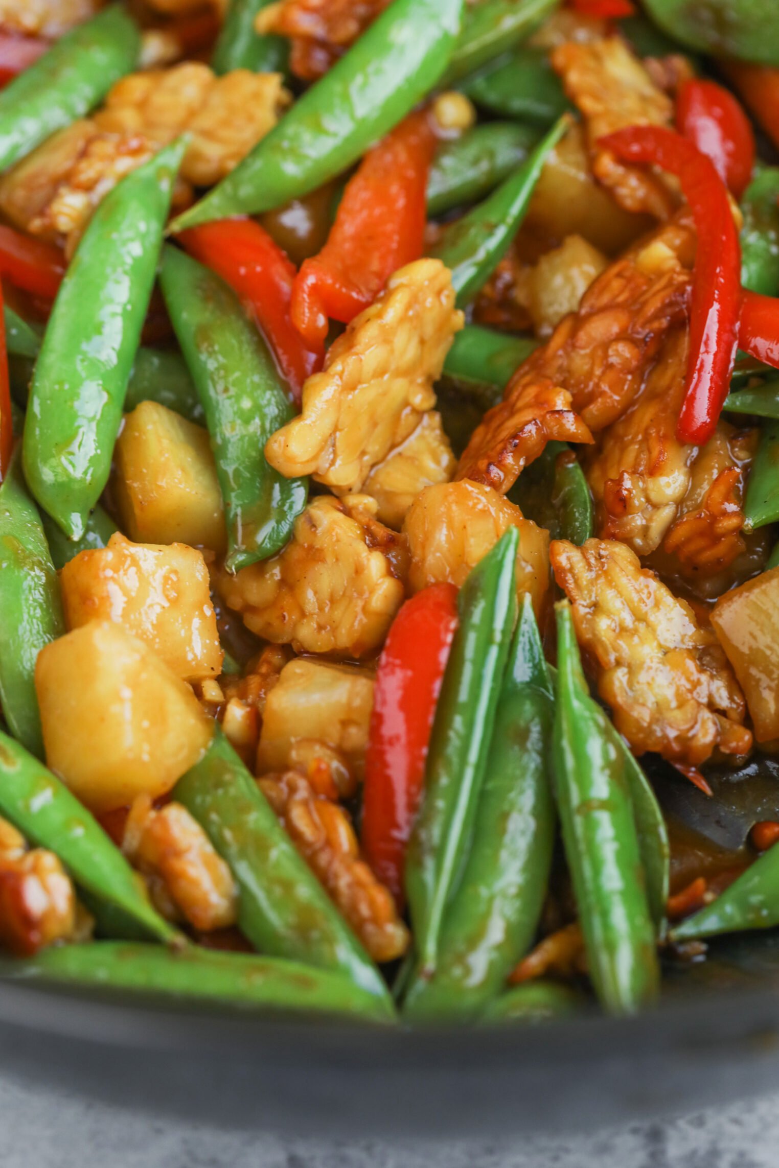 Teriyaki Tempeh Stir Fry 8 A Close-Up Of A Vibrant Tempeh Stir Fry Featuring Snap Peas, Red Bell Pepper Strips, Pineapple Chunks, And Pieces Of Tempeh Coated In A Glossy Sauce.