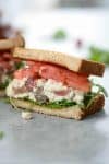 half sandwich of vegan tofu salad with grapes, tomato, arugula, celery