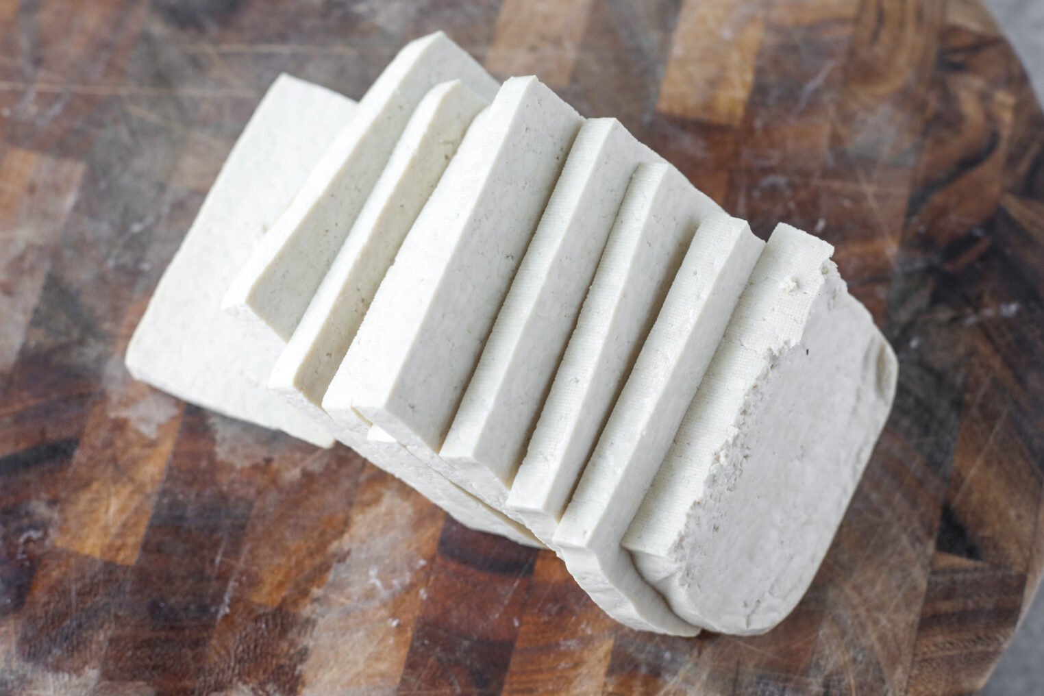 Sliced Tofu Arranged On A Wooden Cutting Board, Showing Several Even, Rectangular Pieces With A Smooth, White Texture—Perfect For Preparing Flavorful Tofu Piccata.