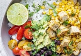 vegan rice bowl with beans, cilantro lime tofu, corn and a lime wedge