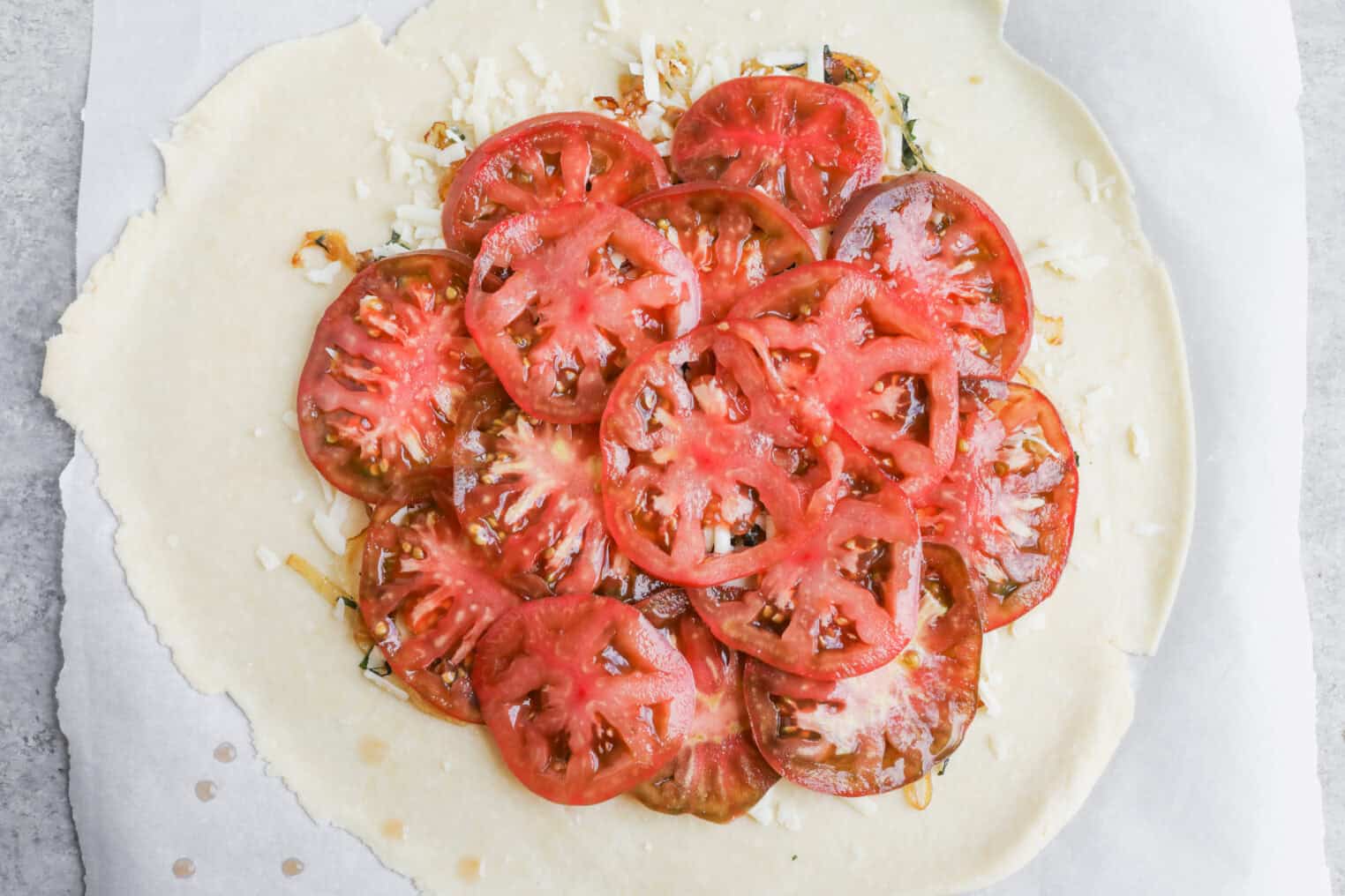 Tomato Galette 8 An Unbaked Tomato Galette With Thinly Sliced Tomatoes Layered Over Cheese And Herbs Rests On Parchment Paper Atop Rolled-Out Dough, Ready For The Oven.