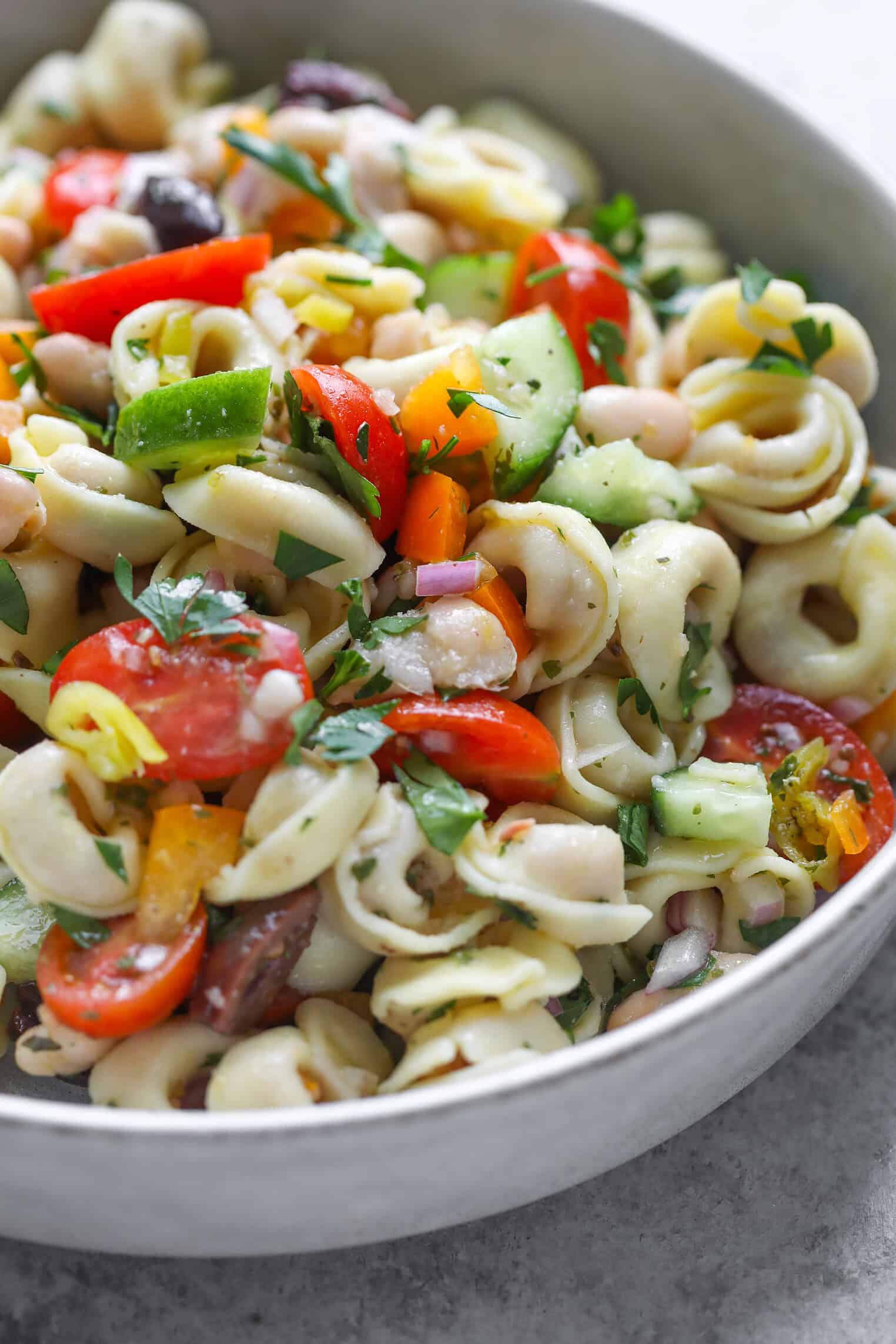 Tortellini Pasta Salad 7 A Close-Up Of A Bowl Filled With Tortellini Pasta Salad, Featuring Colorful Vegetables Like Tomatoes, Bell Peppers, Cucumbers, Olives, And Fresh Herbs For A Fresh And Vibrant Meal.