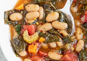 white beans with kale and tomatoes in a bowl