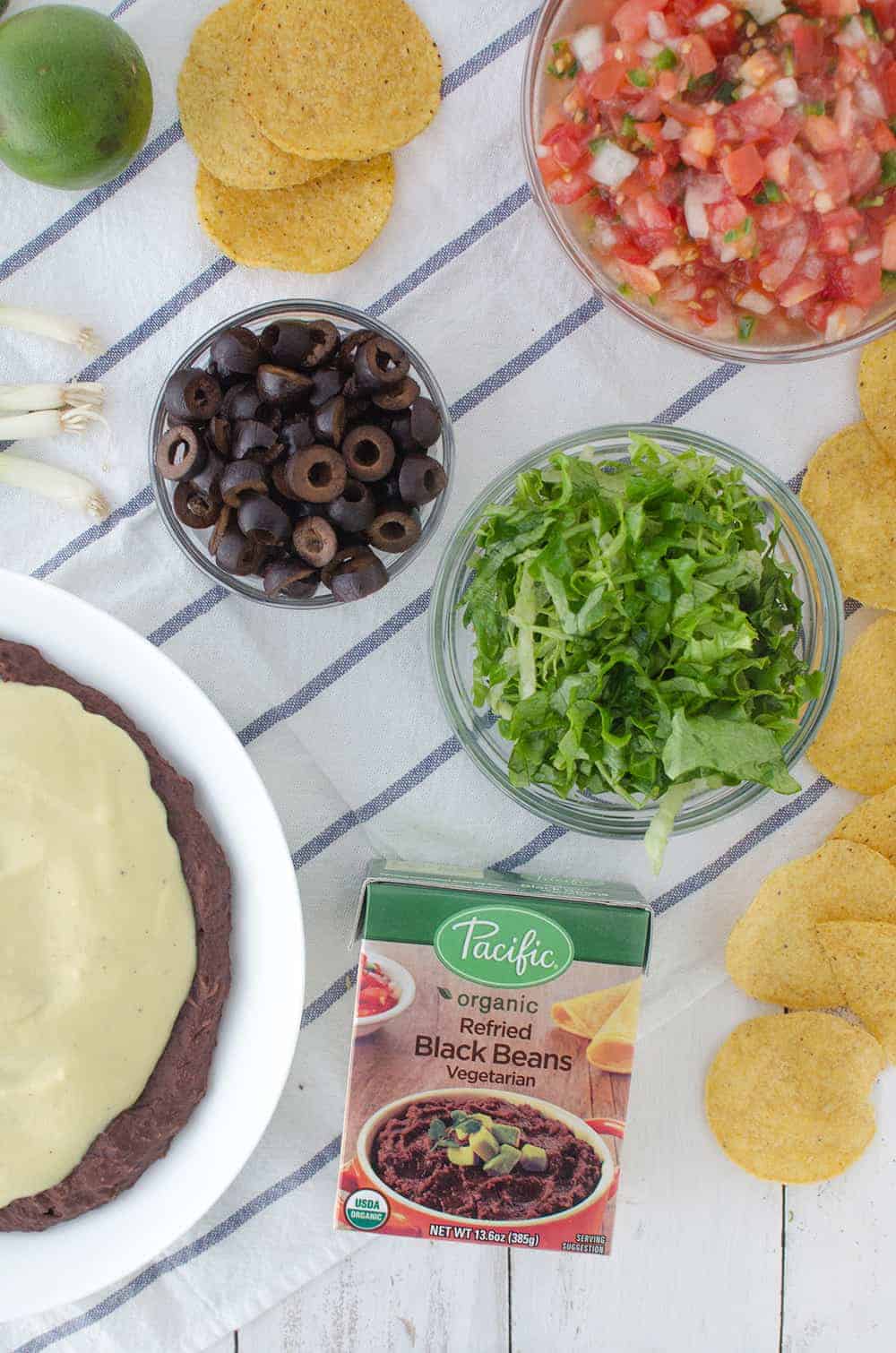 Vegan Mexican 7 Layer Dip! Refried black beans,quick vegan cheese sauce, guacamole, homemade pico de gallo, shredded lettuce, olives, and peppers! A must make for a healthy superbowl! | www.delishknowledge.com