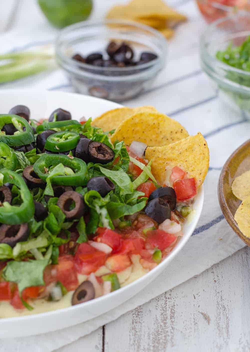 Vegan Mexican 7 Layer Dip! Refried black beans,quick vegan cheese sauce, guacamole, homemade pico de gallo, shredded lettuce, olives, and peppers! A must make for a healthy superbowl! | www.delishknowledge.com