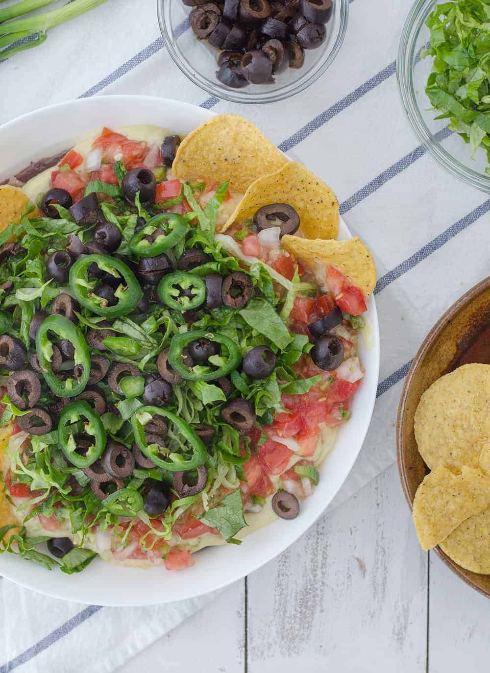 Vegan Mexican 7 Layer Dip! Refried Black Beans,Quick Vegan Cheese Sauce, Guacamole, Homemade Pico De Gallo, Shredded Lettuce, Olives, And Peppers! A Must Make For A Healthy Superbowl! | Www.delishknowledge.com