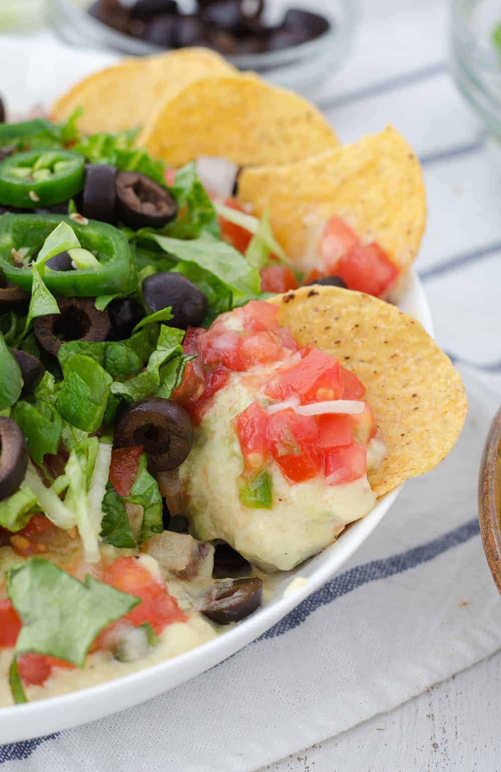 Vegan Mexican 7 Layer Dip! Refried black beans,quick vegan cheese sauce, guacamole, homemade pico de gallo, shredded lettuce, olives, and peppers! A must make for a healthy superbowl! | www.delishknowledge.com