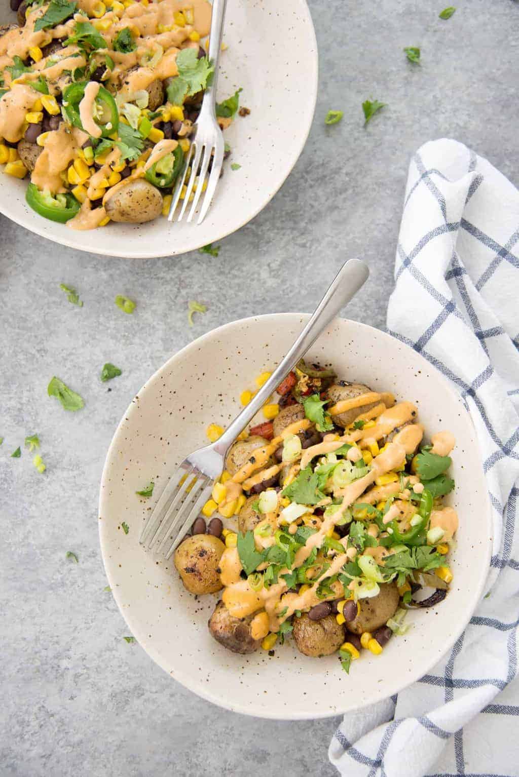 These nacho bowls are SO easy! Grilled potatoes covered with beans, corn, jalapenos and a creamy chipotle sauce. Vegan and Gluten-Free. | www.delishknowledge.com 