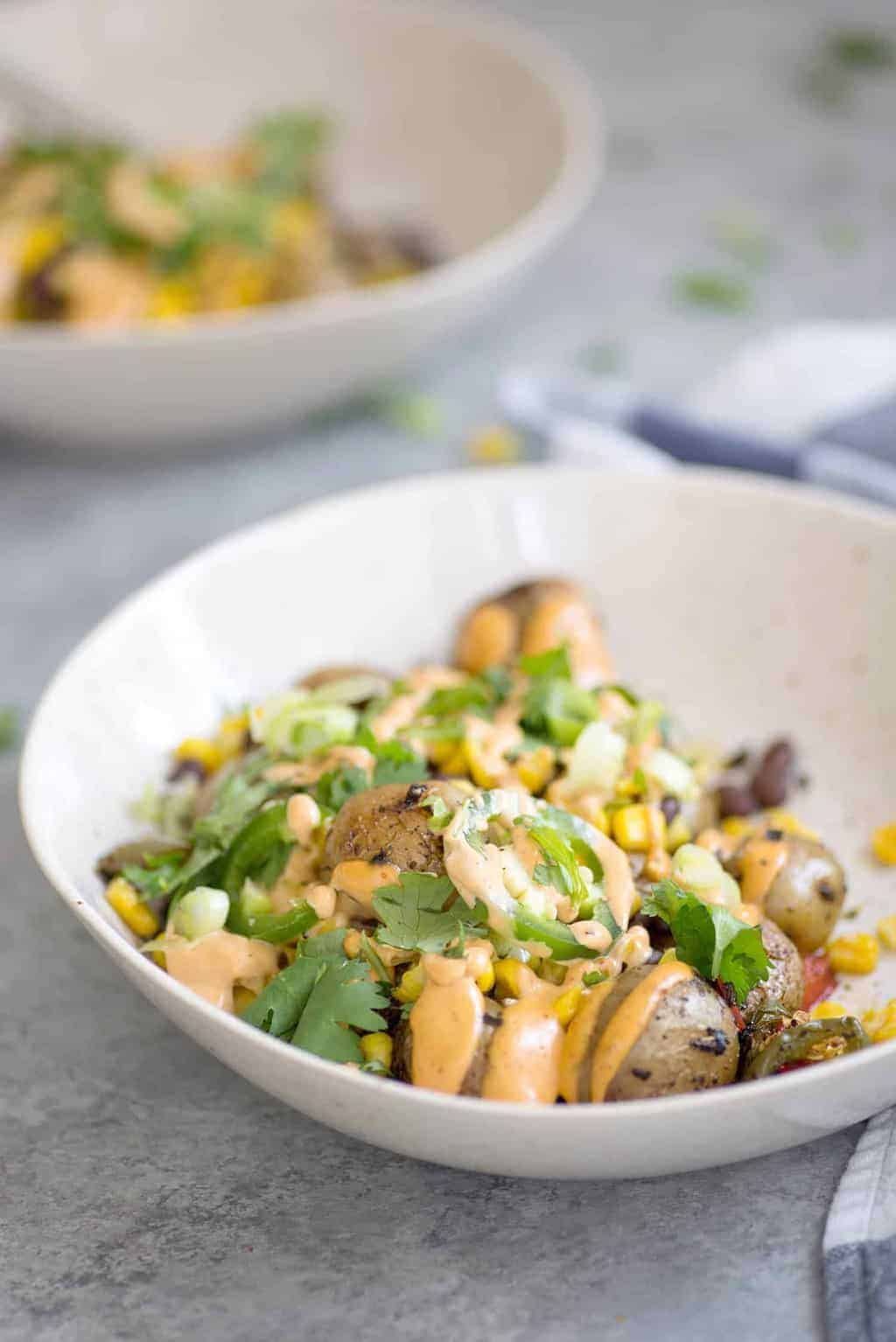These nacho bowls are SO easy! Grilled potatoes covered with beans, corn, jalapenos and a creamy chipotle sauce. Vegan and Gluten-Free. | www.delishknowledge.com 