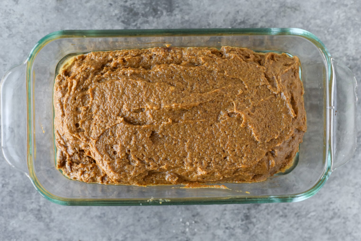 Unbaked Vegan Pumpkin Bread Batter In A Glass Loaf Pan.