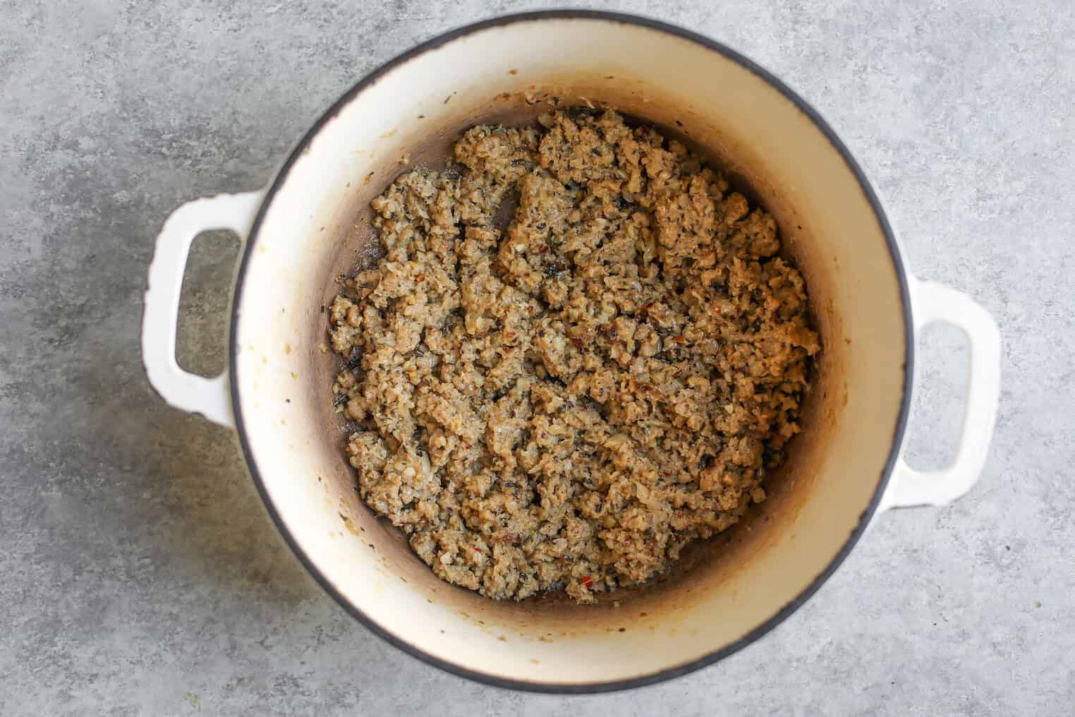 Potato, Spinach and Sausage Soup 4 A White Pot Seen From Above Contains Cooked Ground Meat, Slightly Browned And Crumbled, For A Hearty Spinach Sausage Soup Or Potato Dish, Resting Against A Gray Textured Surface.