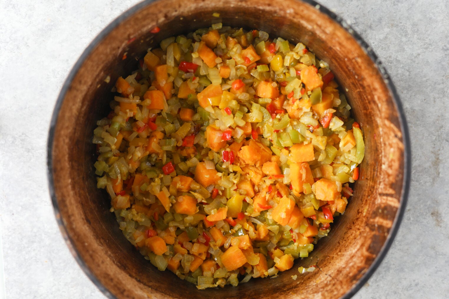 A Pot Filled With A Sautéed Mixture Of Diced Orange Sweet Potatoes, Yellow Onions, And Red Bell Peppers For A Vegetarian Chili.