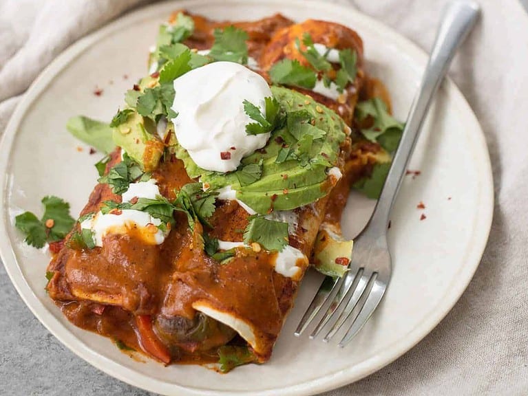 Vegan Fajita Enchiladas! These Enchiladas Are Perfect For Cinco De Mayo. Roasted Peppers, Onions And Beans Covered In A Homemade Enchilada Sauce And Avocado. | Www.delishknowledge.com