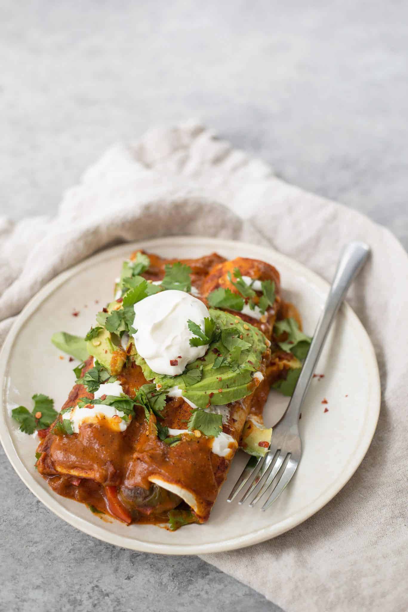 Vegan Fajita Enchiladas! These Enchiladas Are Perfect For Cinco De Mayo. Roasted Peppers, Onions And Beans Covered In A Homemade Enchilada Sauce And Avocado. | Www.delishknowledge.com