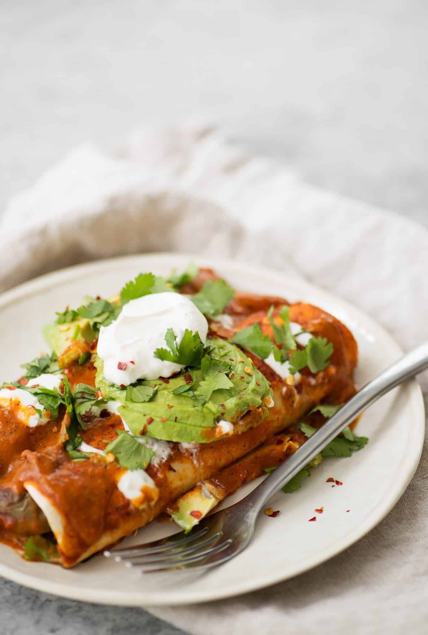 Vegan Fajita Enchiladas! These Enchiladas Are Perfect For Cinco De Mayo. Roasted Peppers, Onions And Beans Covered In A Homemade Enchilada Sauce And Avocado. | Www.delishknowledge.com