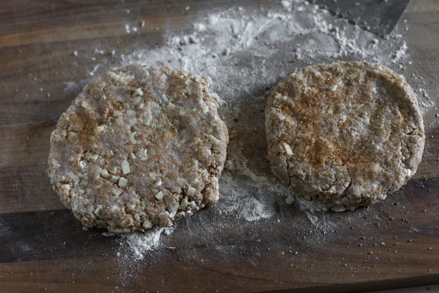 Whole Wheat Apple Scones 8 Two Round Discs Of Raw Apple Scone Dough With Visible Chunks, Dusted With Flour, Rest On A Wooden Surface Lightly Covered With Flour.