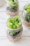 Burrito Bar Mason Jar Salads! Layers of avocado dressing, roasted sweet potato, quinoa, black bean and crispy lettuce. Vegan & Gluten-Free. | www.delishknowledge.com