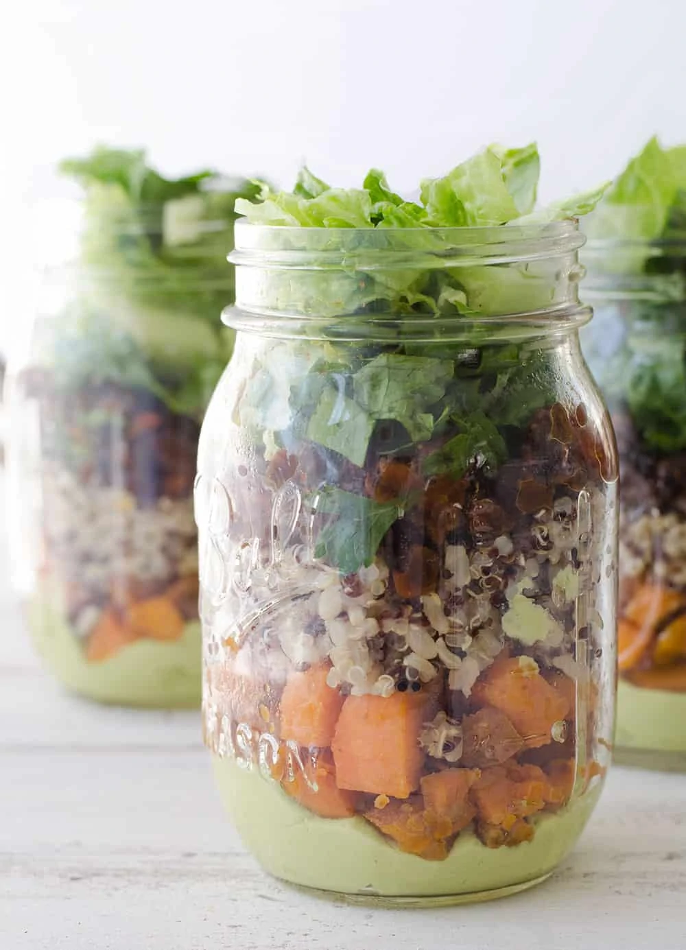 Burrito Bar Mason Jar Salads! Layers of avocado dressing, roasted sweet potato, quinoa, black bean and crispy lettuce. Vegan & Gluten-Free. | www.delishknowledge.com