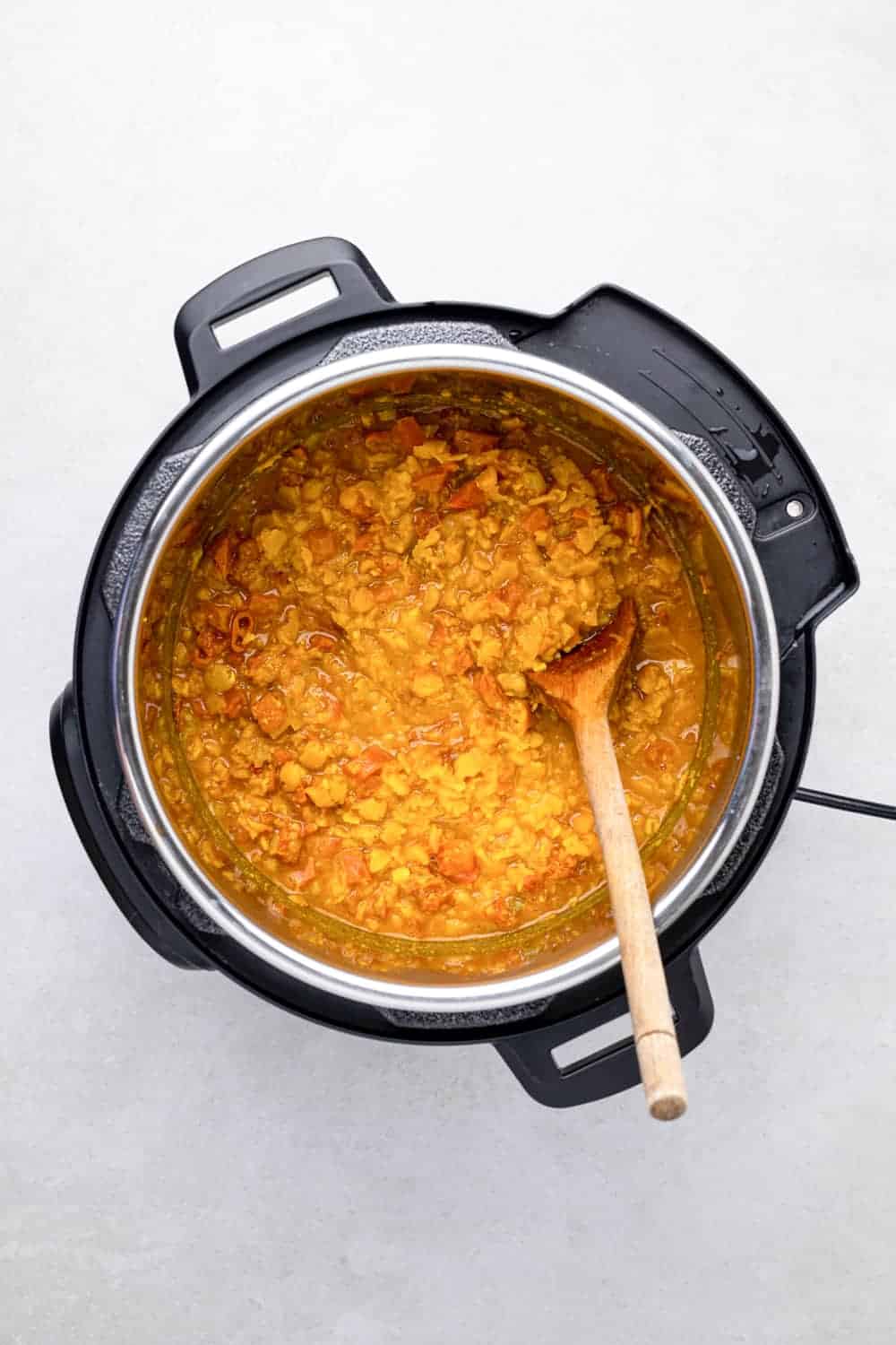 Cooked Dal In The Pot With A Wooden Spoon