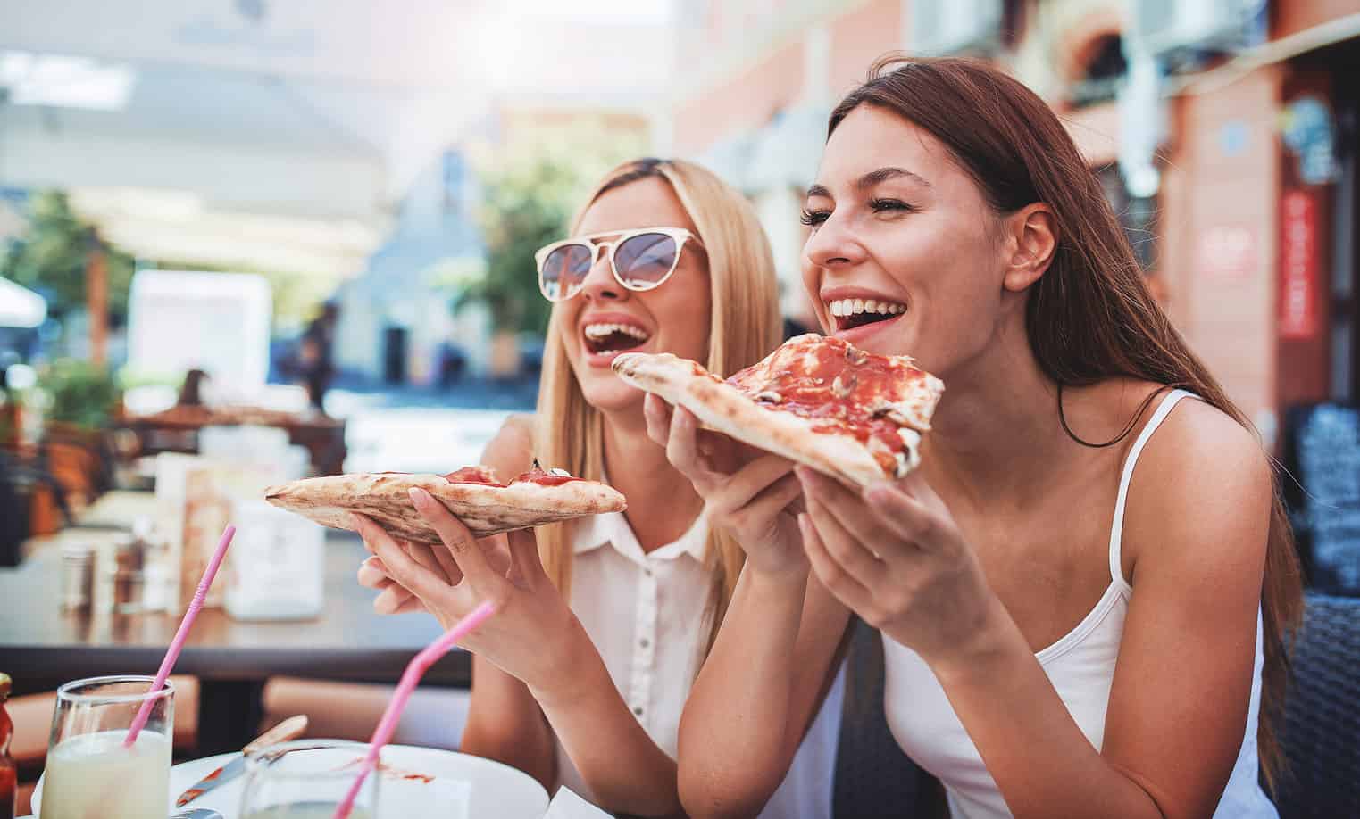 two girls eating a slice of pizza