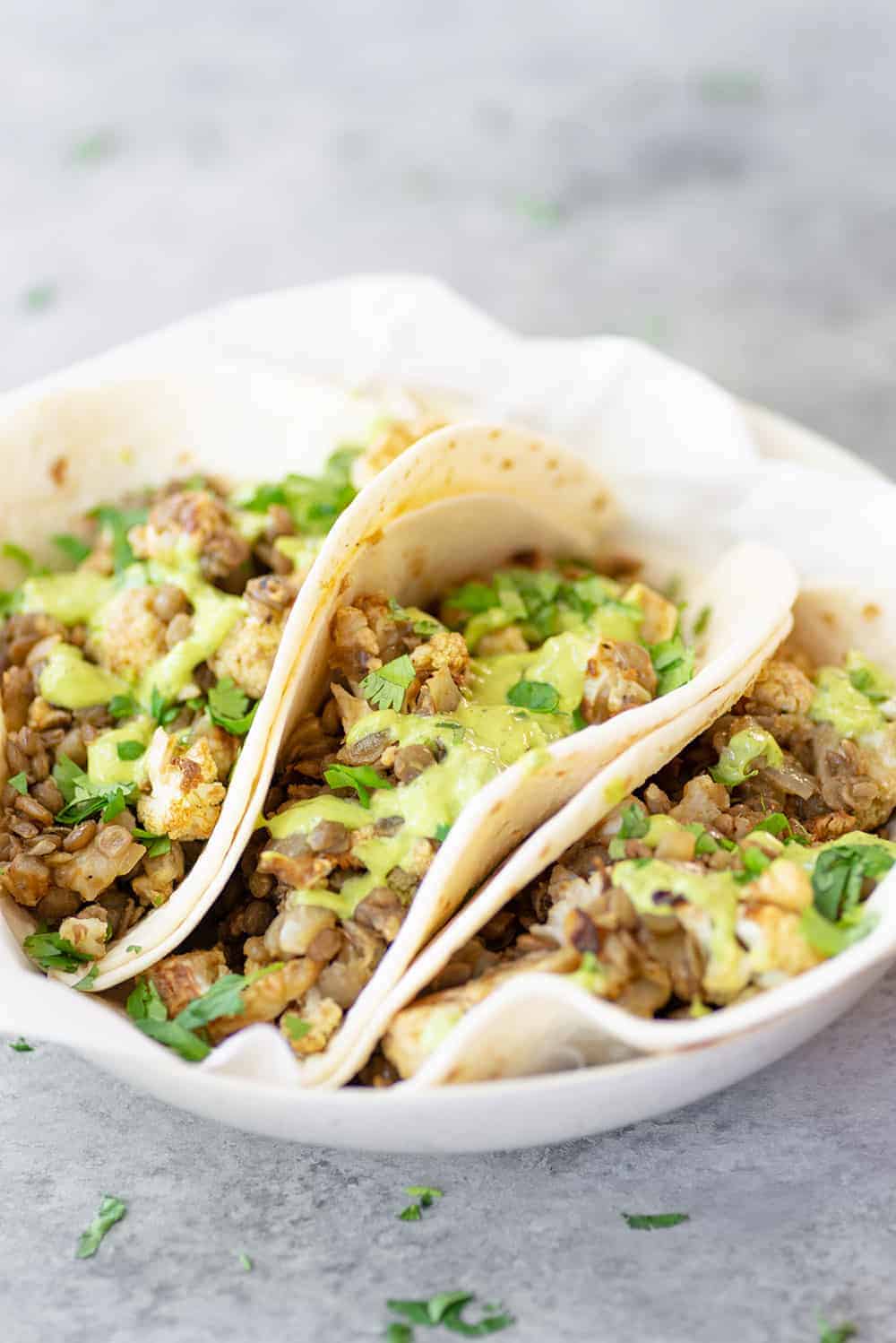 lentil tacos on white plate with green sauce