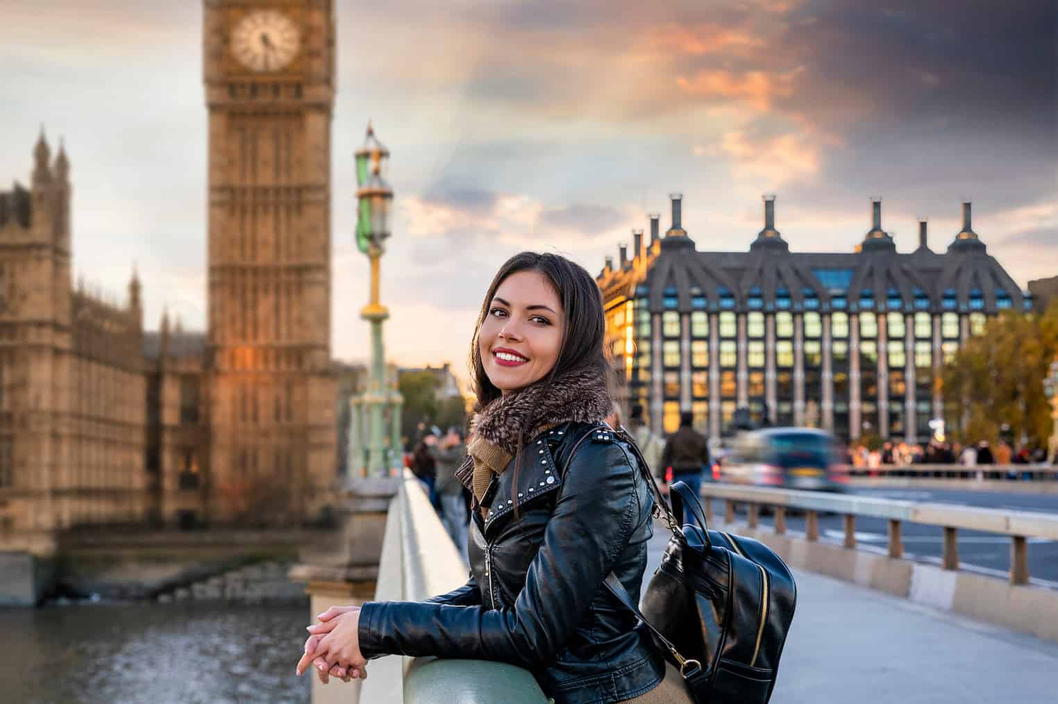 Attractive, young, female London traveler tourist enjoys the view to the Westminster Palace and Big Ben clocktower touring a sightseeing city trip