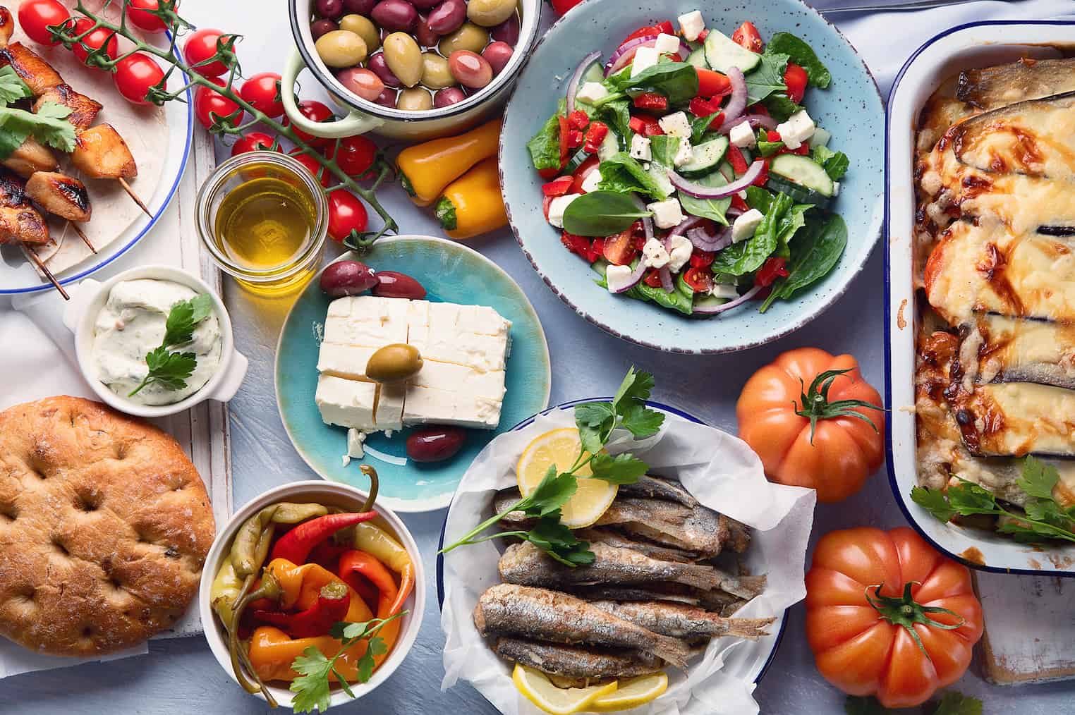 Greek food. Moussaka, meze, souvlaki, fish, pita, greek salad, tzatziki,  olives and vegetables. Traditional different types of greek dishes. Top view, flat lay