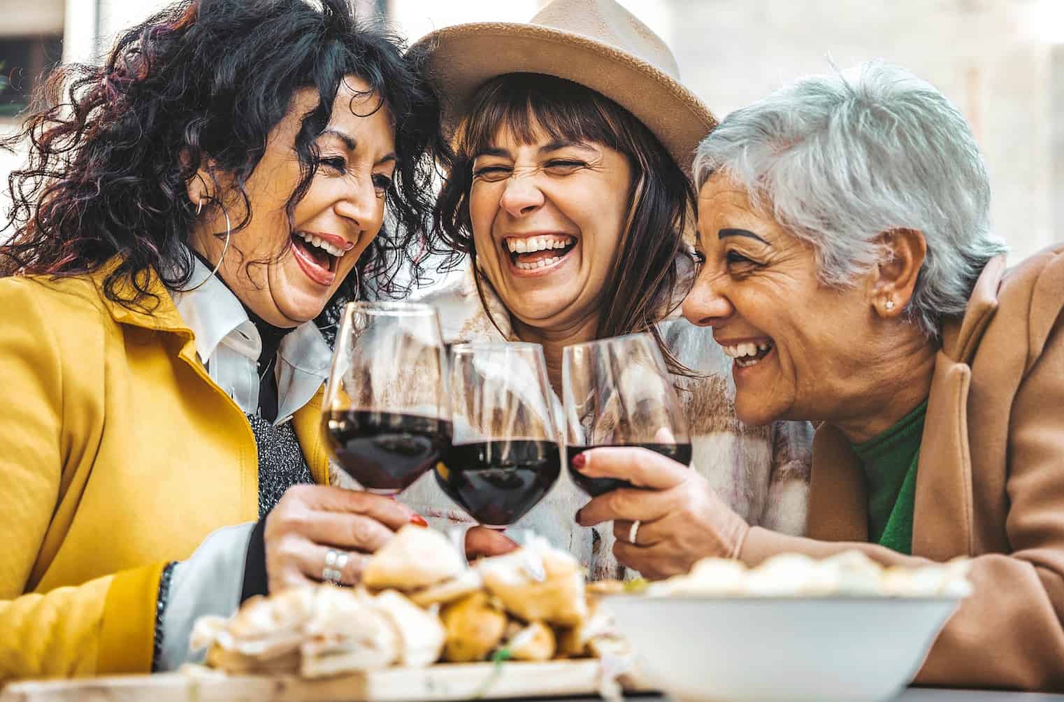 Happy senior women drinking red wine at bar restaurant - Mature people having fun hanging out on city street - Life style concept with older friends smiling and laughing together