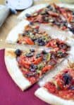 Vegan Puttanesca Pizza! You won't miss the dairy on this one. Salty olives, capers and fresh tomato slices with carmalized onions and mushrooms. Topped with homemade vegan parmasan cheese.