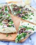 The best dairy-free pizza! Herb and garlic crust topped with creamy white sauce, caramelized onions, fresh herbs and vegan parm sprinkle.