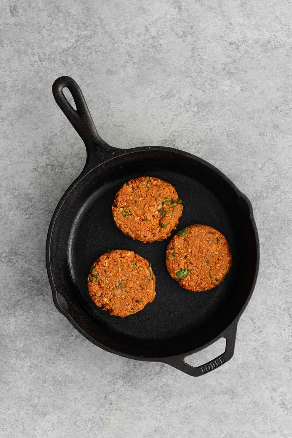 Cast Iron Skillet With Three Sweet Potato And Black Bean Veggie Burger Patties 