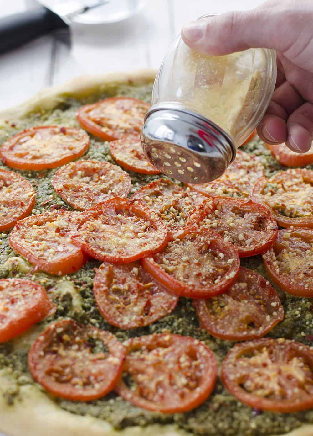 Vegan Parmesan Cheese Being Sprinkled Over Tomatoes