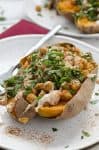 Vegan stuffed sweet potatoes! Roasted sweet potatoes stuffed with spiced chickpeas, garlic tahini sauce and fresh herbs. Gluten-free. | www.delishknowledge.com