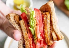 Holding a Tempeh Bacon BLT Sandwiches